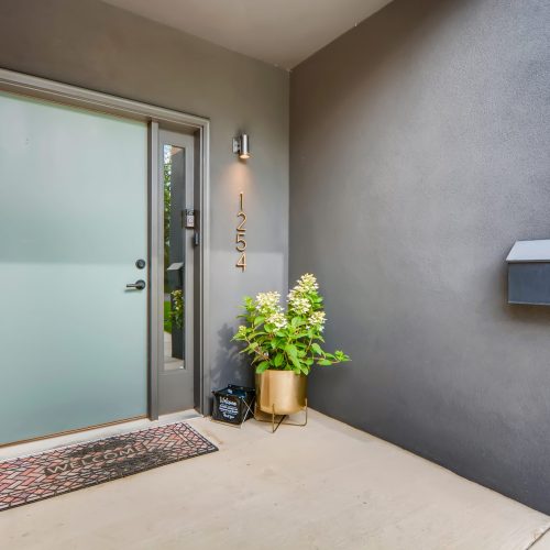 Front door of home for sale with welcome mat and flowers